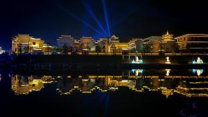 a city at night with a reflection in the water at GUI YUAN ZHEN PIN HOTEL,Approximately 3km away from the east gate of Zhangjiajie National Forest Park,Free Chinese western Breakfast,Free Self-Service Laundry , Attraction Tickets Serivce in advance,Free one-way shuttle service for 4 nights or more in Zhangjiajie