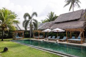 a resort with a swimming pool with chairs and umbrellas at Nativo Lombok Hotel in Kuta Lombok