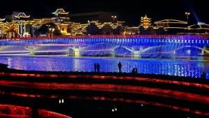 a group of people standing in front of a fountain at night at 铂曼智慧酒店-Near the east gate of the Forest Park, about a 10-minute walk-There is a beautiful small river at the entrance-offers free self-service laundry -Attraction Tickets Serivce in advance-Free one-way shuttle service for 4 nights or more in Zhangjiajie
