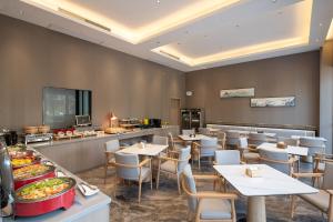 a restaurant with tables and chairs and a buffet at Bernard Hotel Putian Xinghuafu Historical and Cultural Street Branch in Putian