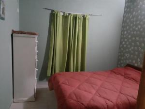 Un dormitorio con una cama y una cortina verde. en Departamento para 5 personas con pileta, en Villa Gesell 1 foto más