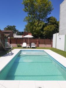 una piscina con dos sillas y una sombrilla en Departamento para 5 personas con pileta, en Villa Gesell