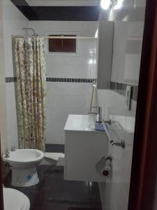 Un baño blanco con inodoro y lavabo. en Departamento para 5 personas con pileta, en Villa Gesell