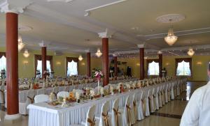 Długa sala bankietowa z białymi stołami i krzesłami w obiekcie Hotelik Karter w Warszawie