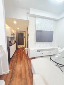 a white living room with a large tv on a wall at Condo Hotel Walking Abreeza Mall and Near SM Lanang in Davao City