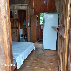 Zimmer mit einem Kühlschrank und einem Bett. in der Unterkunft Chalés Vitória in Trindade + 21 Fotos