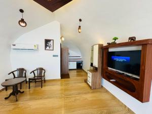 KappilにあるMaadathil Cottages & Beach Resortのリビングルーム(テレビ、テーブル、椅子付)