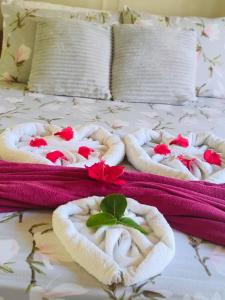two towels with flowers in them on a bed at Villa da Apa in Japaratinga