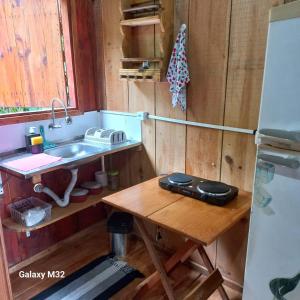 a kitchen with a sink and a wooden table at Chalés Vitória in Trindade +21 photos