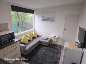 a living room with a couch and a window at Manuki Tiny Retreat - Private stay Christchurch in Christchurch