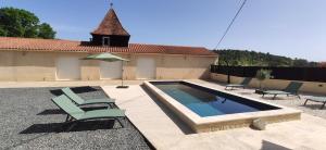 a swimming pool with two chairs and an umbrella at Villa Les Combes avec piscine chauffée in Proissans