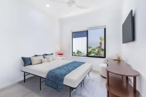 ein weißes Schlafzimmer mit einem Bett und einem Fenster in der Unterkunft Stylish Family Retreat in Varsity by Housemark Escapes in Gold Coast