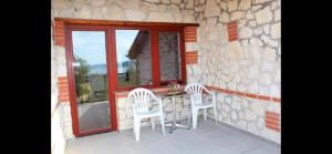 a patio with a table and two chairs and a window at Къщи за гости Илиеви , Цигов Чарк in Batak