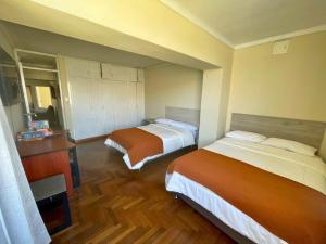 ein Hotelzimmer mit zwei Betten und einem Fernseher in der Unterkunft Apartamento en Tacna Amplio, Lindo y Céntrico in Tacna + 1 Foto