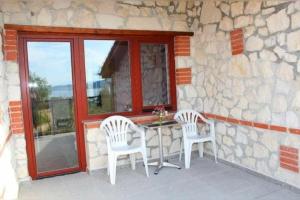a patio with two chairs and a table and a window at Къщи за гости Илиеви , Цигов Чарк in Batak