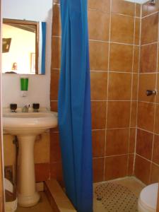 baño con lavabo y cortina de ducha azul en Samay Wasi Hostel I, en Cusco