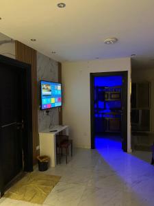 a living room with a television and a door with blue lights at ستديو فاخر بحدائق الاهرام in Ghaţāţī