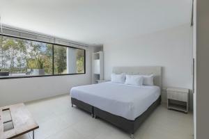 une chambre avec un lit blanc et une grande fenêtre dans l'établissement Luxé Cabañas, à Guatapé 59 autres photos