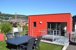 a red house with a table and chairs in front of it at La boîte rouge in Stavelot