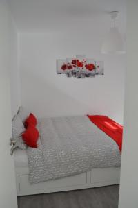 um quarto branco com uma cama com almofadas vermelhas em La boîte rouge em Stavelot