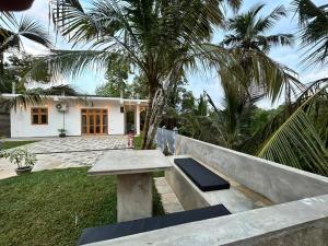 eine Bank vor einem Haus mit Palmen in der Unterkunft Villa Tesh Hiriketiya in Dikwella + 11 Fotos