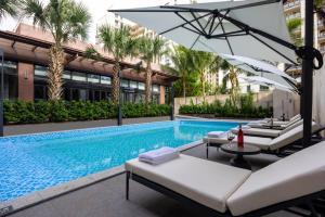 einem Pool mit Stühlen und einem Sonnenschirm neben einem Gebäude in der Unterkunft Four Points by Sheraton Haikou International Airport in Haikou