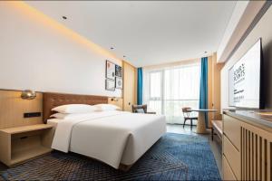 ein Hotelzimmer mit einem großen weißen Bett und einem Schreibtisch in der Unterkunft Four Points by Sheraton Haikou International Airport in Haikou