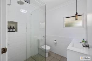 a white bathroom with a toilet and a sink at Classic Beach House on Surfside - Pet Friendly in Pottsville +12 photos