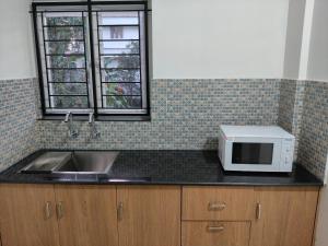 a kitchen with a sink and a microwave on a counter at ElShium Homes in Cochin