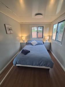a bedroom with a bed with blue sheets and two windows at Country Cottage of Yesteryear 