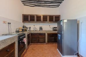 a kitchen with a stainless steel refrigerator and wooden cabinets at Auregi Villas - 2 and 3 bedroom near Diani Beach in Diani Beach