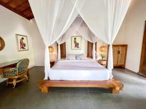 une chambre avec un lit blanc à baldaquin dans l'établissement Seseh Beach Retreat Villas, à Canggu