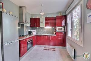 a kitchen with red cabinets and a refrigerator at Le jardin in Plestin-les-Grèves +26 photos