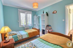 a bedroom with two beds and blue walls at Le jardin in Plestin-les-Grèves