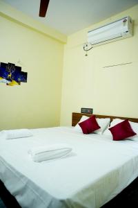 a bedroom with a large white bed with red pillows at Entire 1bhk Home - Kumbha Nivas Homestay in Kumbakonam