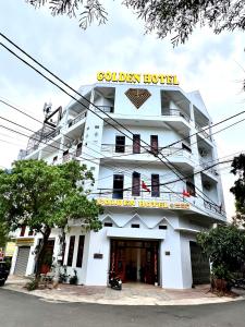 a white building with a yellow sign on it at Golden Hotel in Buon Ma Thuot