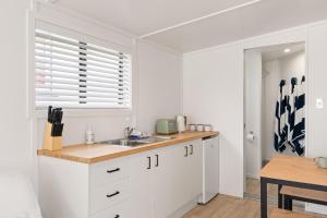 a kitchen with white cabinets and a sink and a window at Beachfront Studio Steps to the Sand in Gisborne