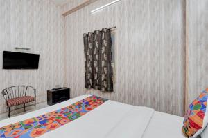 a bedroom with a bed and a chair and a television at FabHotel Citi Residenci in Varanasi +19 photos