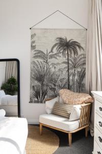 Un dormitorio con una silla y un cuadro en la pared. en Renovated 3BR Apartment in CBD, en Gisborne