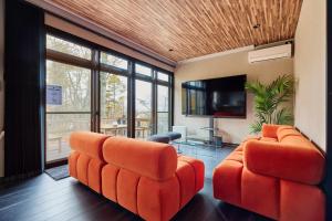 sala de estar con 2 sillas de color naranja y TV de pantalla plana en 富士山を見ながらサウナBBQ The No10 MtFuji Forest House, en Yamanakako