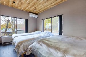 Dos camas en una habitación con ventana. en 富士山を見ながらサウナBBQ The No10 MtFuji Forest House, en Yamanakako