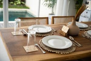 a wooden table with plates and utensils on it at Swamis Villa in Tumbak Bayuh