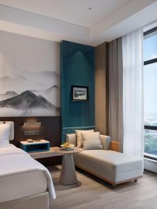ein Hotelzimmer mit einer Couch und einem Tisch in der Unterkunft Zhangjiagang Wanda Jinhua Hotel 