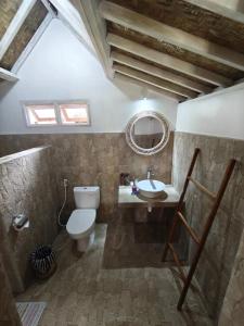 a bathroom with a toilet and a sink and a mirror at Tetebatu Flush Harmony in Tetebatu