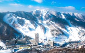 una vista aérea de una ciudad con montañas cubiertas de nieve en Phoenix Resort Pyeongchang, en Pyeongchang