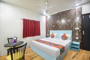 ein Schlafzimmer mit einem Bett und einem Tisch mit einem roten Vorhang in der Unterkunft FabHotel Red Apple in Neu-Delhi