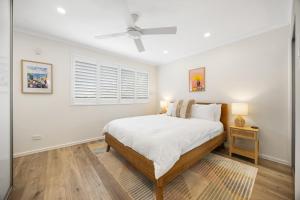 a white bedroom with a bed and a window at Hazy Shores Escape - Breezy Coastal Stay near Henley Square in Henley Beach