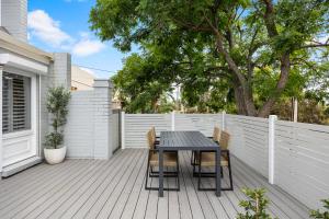 a black table and chairs on a wooden deck at Hazy Shores Escape - Breezy Coastal Stay near Henley Square in Henley Beach