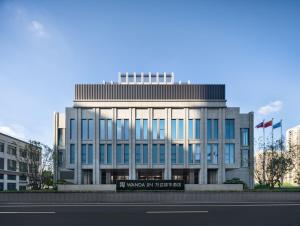 ein Gebäude mit einem Schild davor in der Unterkunft Zhangjiagang Wanda Jinhua Hotel 