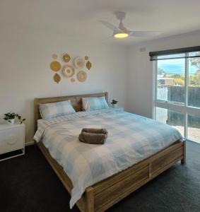 Un dormitorio con una cama grande con una ventana grande. en Sitara Cottage, en Yanakie